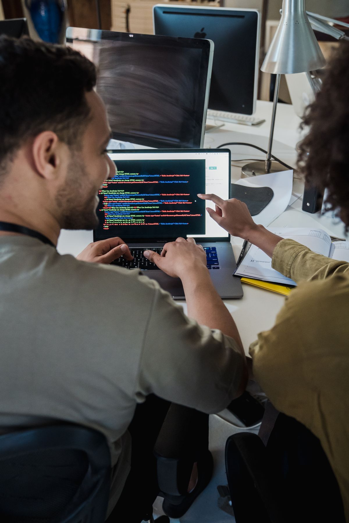 Duas pessoas revisando código juntas em um notebook